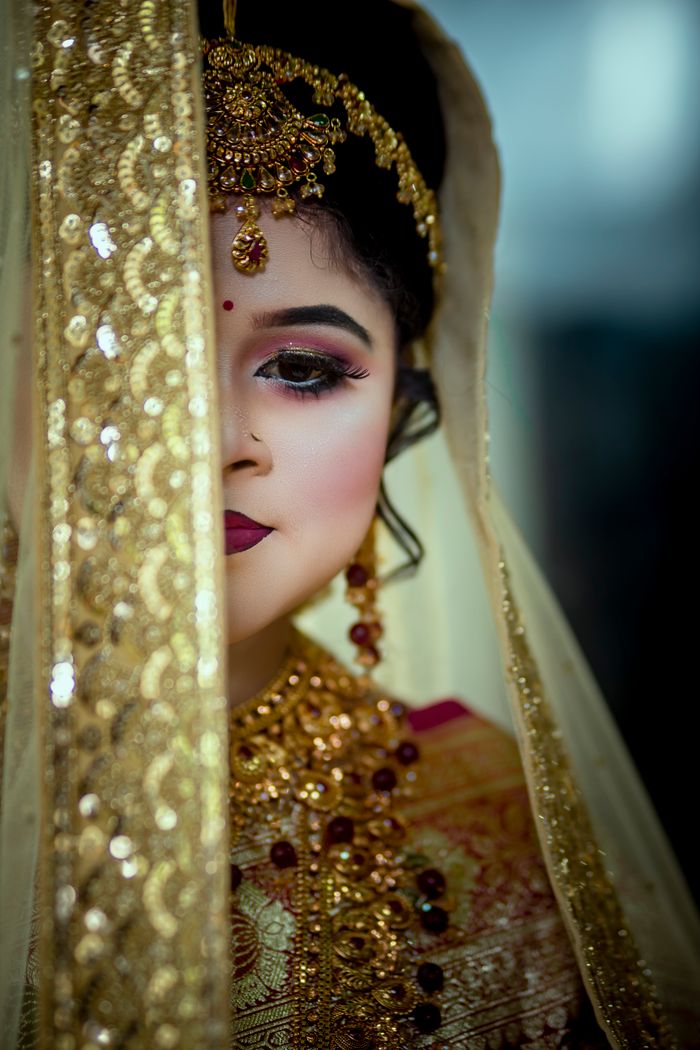 Captivating portrait of a young bride with an elaborate headdress, gold jewelry, and ornate veil.