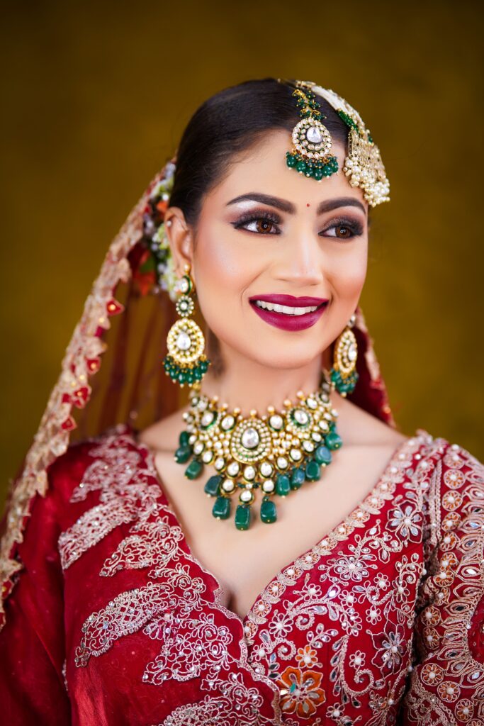 Beautiful Indian bride in red sari with stunning jewelry and intricate embroidery.