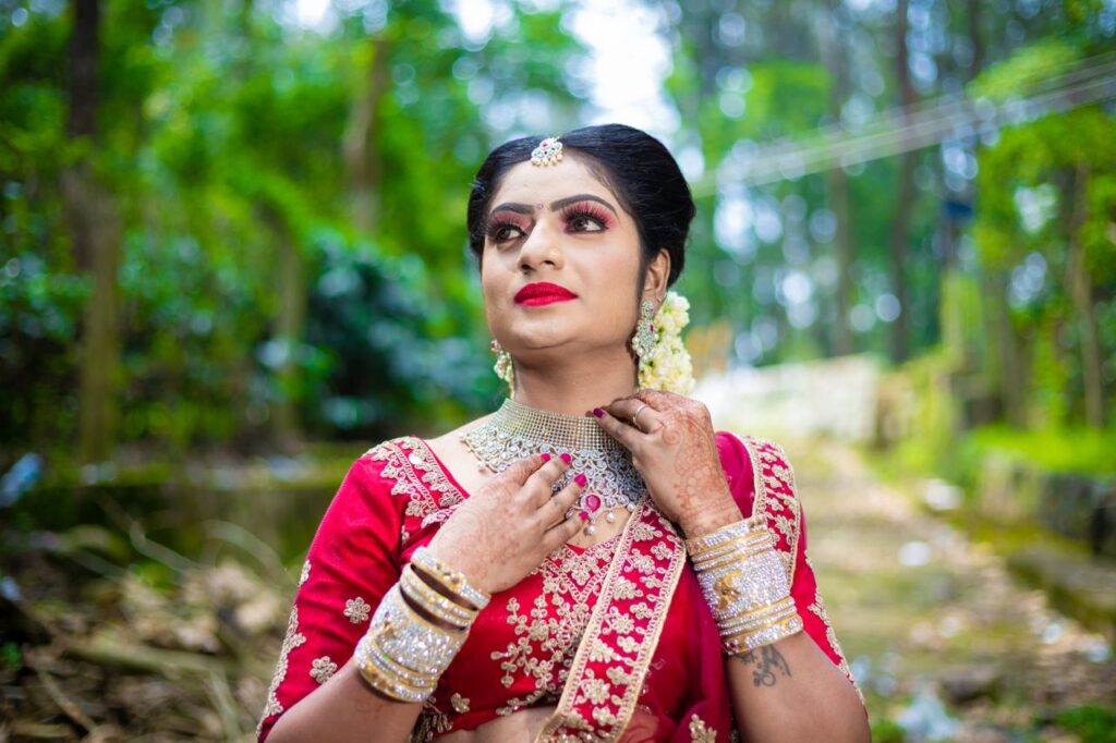 Beautiful bride in traditional attire posing outdoors surrounded by lush greenery.