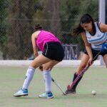 Intense game of field hockey with two women competing on an outdoor court.