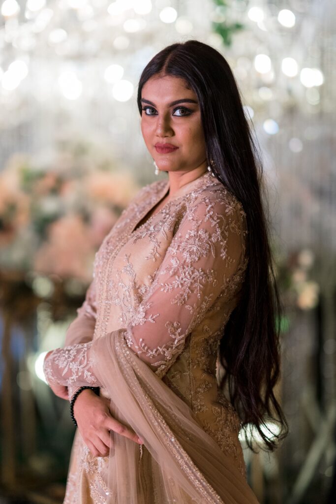 Elegantly dressed woman in traditional attire posing indoors with a soft focus background